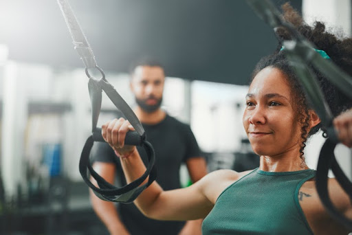 Shot of a woman using suspension straps while working out in the gym