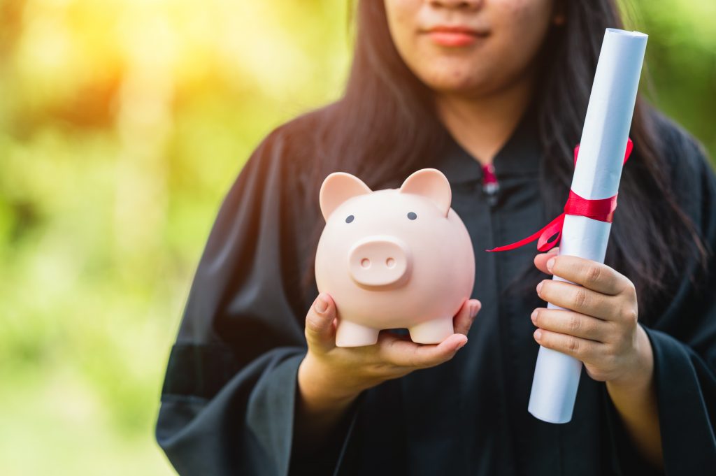 College graduate holding piggy bank and diploma