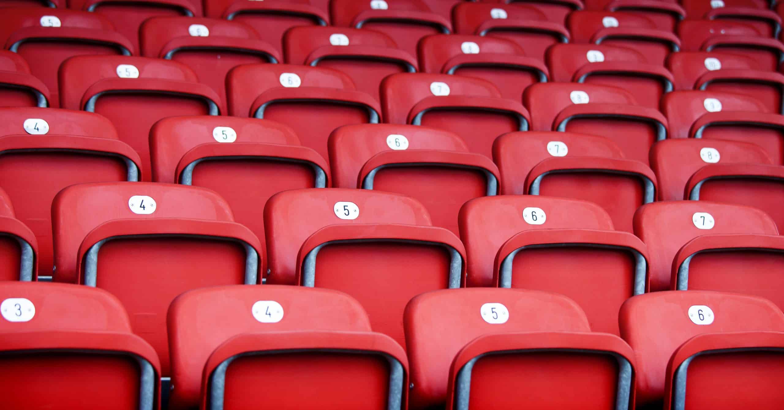 a photo of several rows of empty red seats at a stadium venue