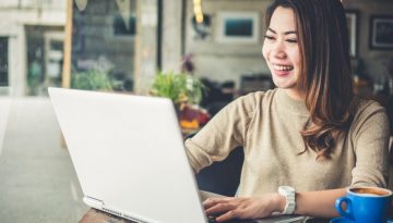 Young professional woman smiling using video as communication solution from laptop.